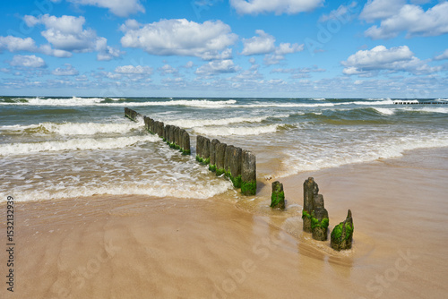 Baltic Sea - blue sky, wave sea and wooden waterbreak.	