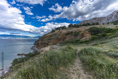 Fototapeta Naklejka Na Ścianę i Meble -  Green grass in a clearing, rest on a trail near the town of Baska, view of the bay and the city panorama