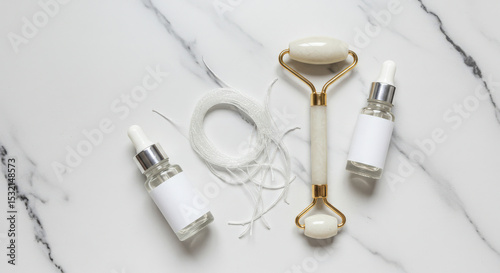 Collagen Threads Next to Face Roller and Serum Bottles Flat Lay on Marble