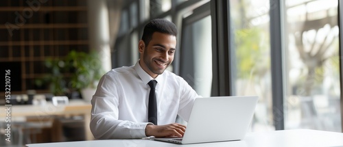 Young arabic manager is concentrating on his laptop in a modern office, showcasing professionalism and a tech-savvy work environment. photo