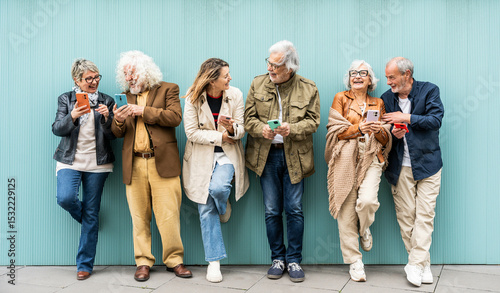 Fotografie Group of senior people using technology devices together standing on a blue wall
