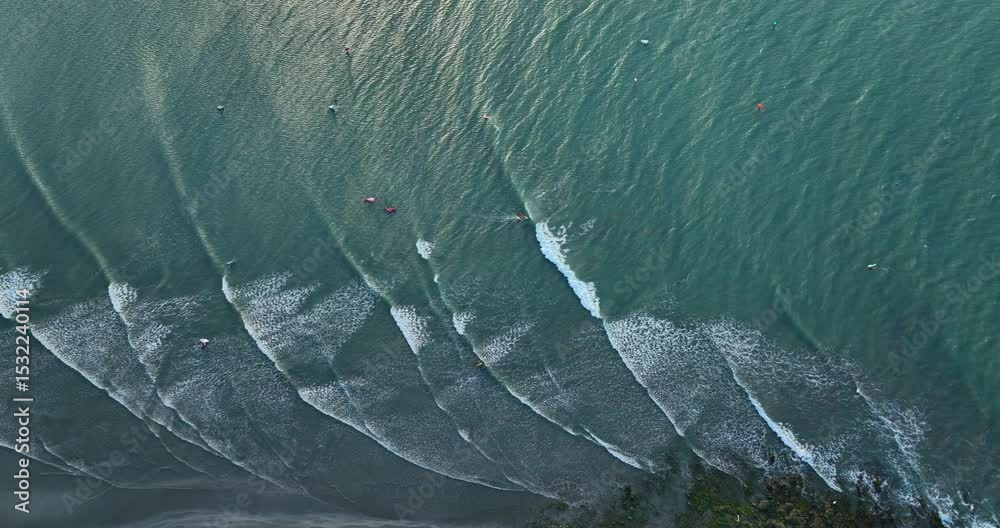 Turquoise waves form parallel lines and break near the shore in Jericoacoara, Brazil. Slow motion a top-down drone aerial