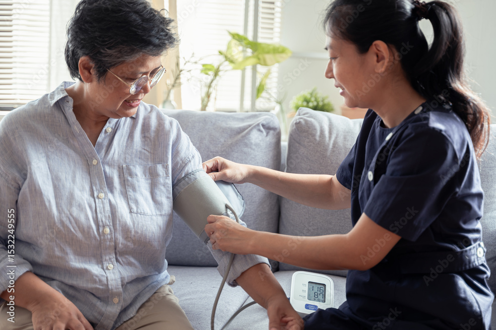 Fototapeta premium Young Asian woman nurse take care senior woman at nursing home, checking blood pressure for observe health condition. Healthy senior home care or medical concept.