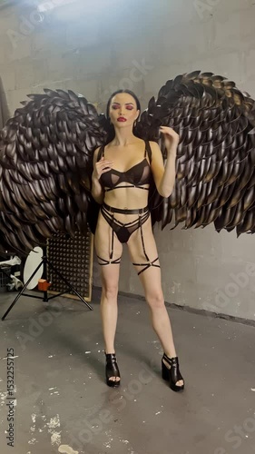 Woman poses elegantly in a studio with dramatic feathered wings