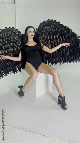 Woman showcasing stunning black feather wings in a beauty studio setting