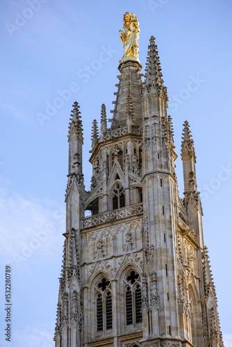 The Tour Pey Berland, featuring a golden Virgin Mary statue, stands beside the Cathédrale Saint-Andre, framed by autumn leaves. Bordeaux. France