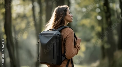 Woman walking through dense forest carrying sleek black backpack