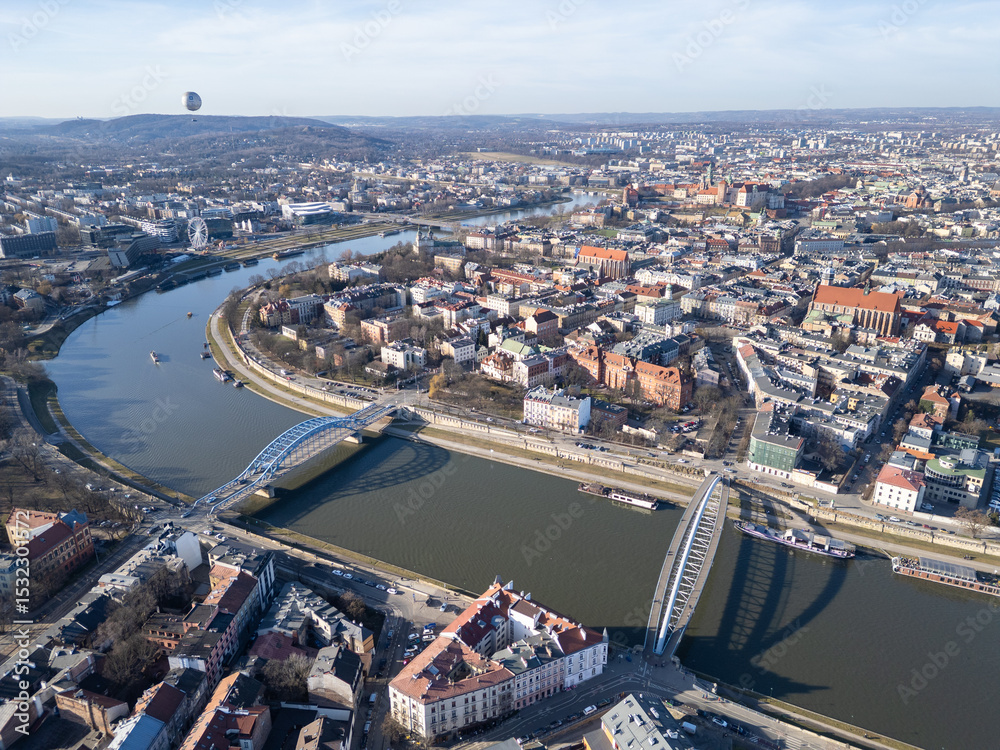 Naklejka premium Krakow, Poland: Aerial view of the historic Kazimierz district and the Father Bernatek’s Bridge over the Vistula river in Krakow on a sunny winter day in Poland.