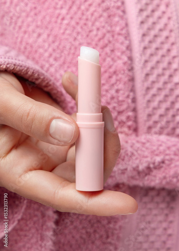 Woman in pink bathrobe holding in hand opened lip balm stick closeup, girly cosmetic mockup