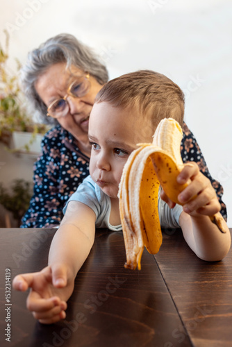 2,5 YO Jewish child holding banana with his 80 year old grandmother.