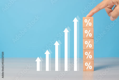 Interest rates and dividends, hand picking wooden blocks with percentage symbol and up arrow, returns on stocks and mutual funds, long term investments for retirement