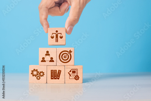 Wooden cube with ethics symbol held in hand. Represents corporate responsibility, integrity, and compliance in business practices.