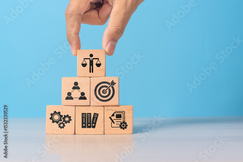 Hand holding wooden block with Ethical icons, business ethics and corporate compliance concept