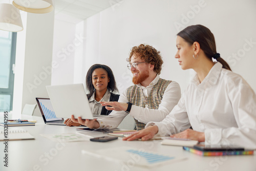 A diverse and dynamic team is actively engaging in a collaborative work session utilizing their laptops and tablets