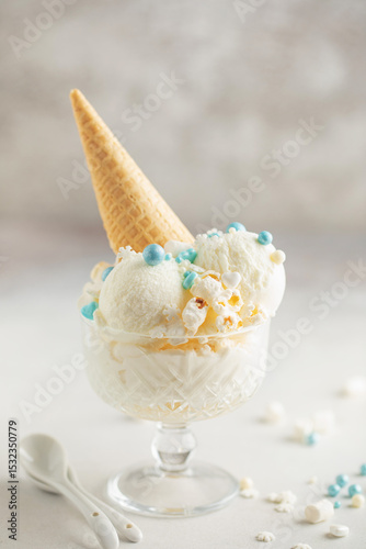 Vanilla ice cream balls with popcorn and pastry sprinkles in a cream bowl on a light background