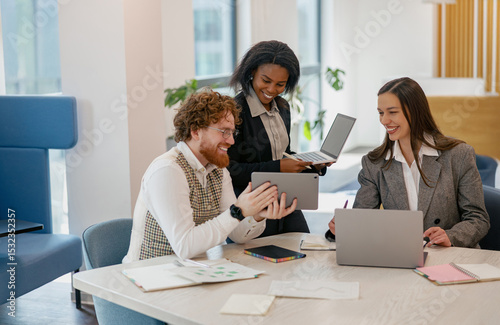 A diverse team in a modern office collaborates, exchanging innovative tech and fresh creative ideas