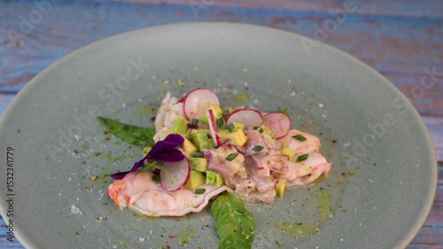 Delightful ceviche made with fresh dorade and shrimp, complemented by avocado and radish, garnished with an edible flower on a serene green plate.