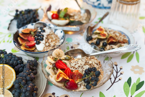 Fotografi A set of cozy bowls of oatmeal topped with fresh fig, banana, strawberries, and black grapes