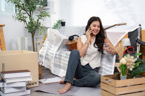 Moving Home. Woman on the phone enjoying a drink while settling in.