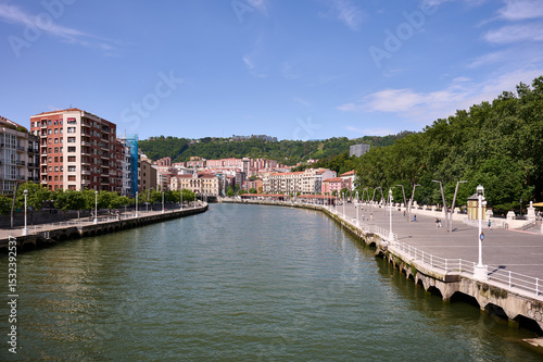 Scenic view of Nervion river, residential buildings, and promenade in Bilbao, spain, on a sunny summer day