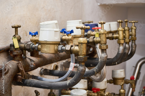 Close up of water meters and valves regulating water flow in a residential building, ensuring accurate measurement of individual consumption photo