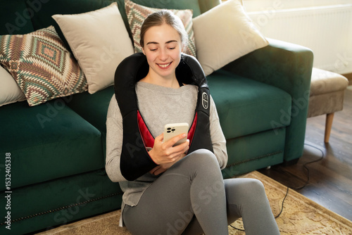 Schilderij op canvas Young woman relaxing at home with electric neck and shoulder massager while usin