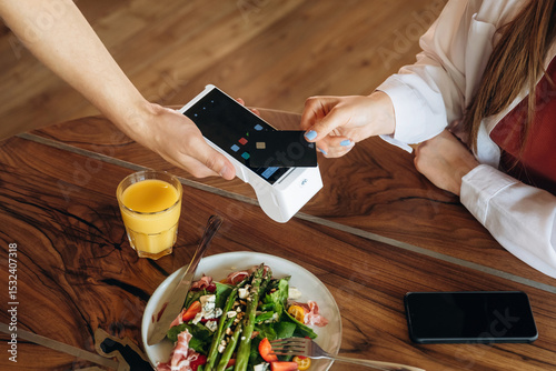 Top close up view. Woman is paying for meal by wireless payment in the cafe restaurant photo