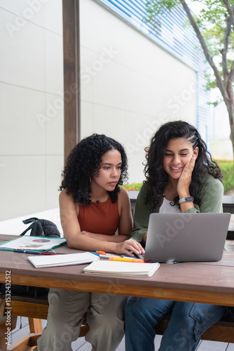 University students collaborating on project with laptop outdoors