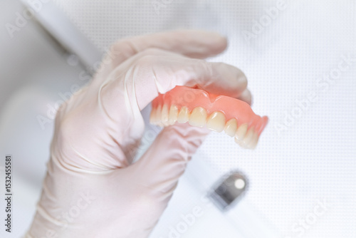 Removable dental prosthesis with visible wear and gloved hand