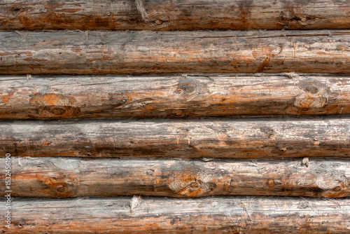 A wooden log wall of an old barn in a village, with its natural background and wooden texture.