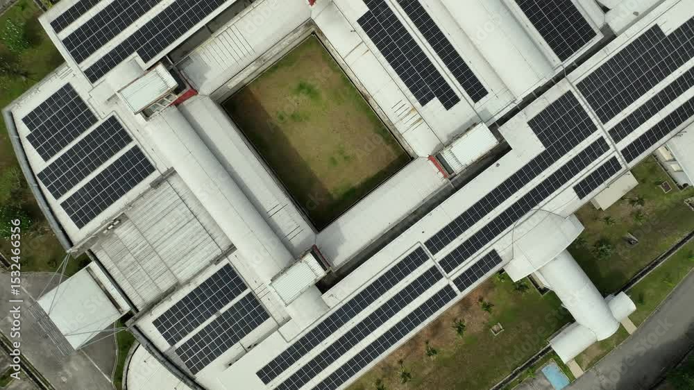 Solar panel installation on a large building in a green urban area during daylight hours