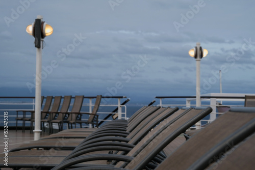 Outdoor promenade boat sun deck onboard modern luxury cruiseship cruise ship ocean liner with teak wood loungers and deck chairs for guests passengers with ocean views