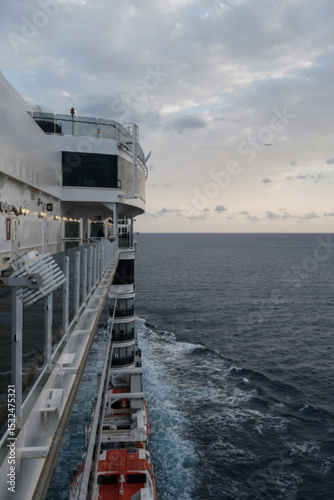 Outdoor promenade boat sun deck onboard modern luxury cruiseship cruise ship ocean liner with teak wood loungers and deck chairs for guests passengers with ocean views