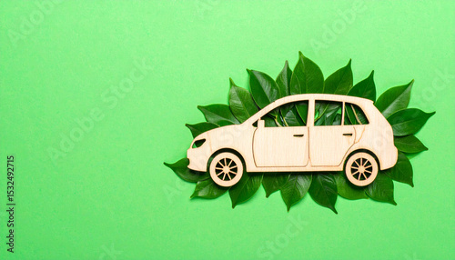 a decorative craft resembling a paper car with wheels attached to it, adorned with a small green leaf on its front side, placed against a backdrop that transitions from green at the bottom to blue at