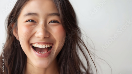 portrait of a beautiful Asian woman with a face full of excitement and joy, neutral gray background