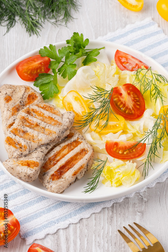 Healthy keto, ketogenic lunch with grilled chicken meat and organic tomatoes and greens. Roasted chicken breast, fillet and fresh vegetable salad on a white wooden table, copy space