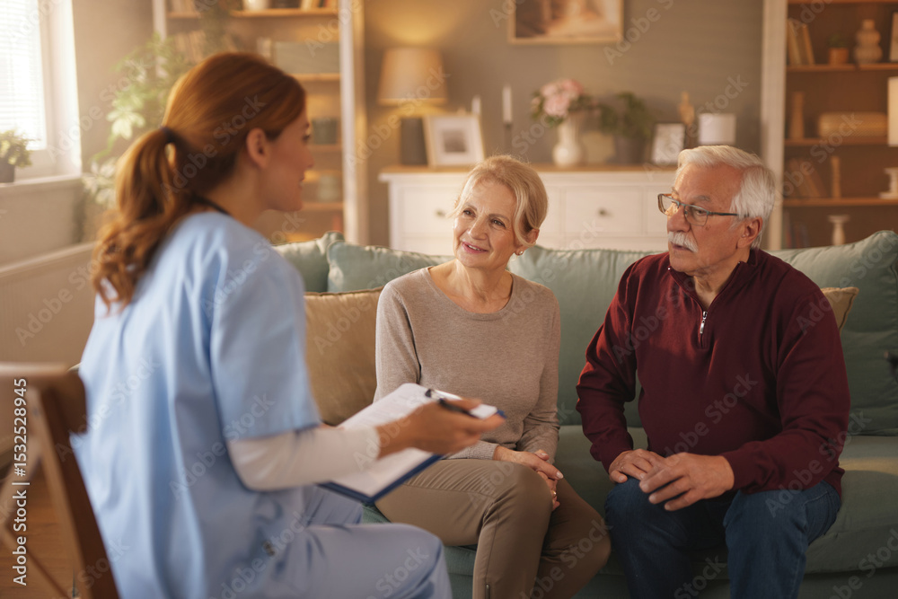 Obraz premium A home health care nurse in light blue scrubs sits on a chair talking to an elderly Caucasian couple seated on a teal sofa in their living room during the day. The nurse holds a clipboard.