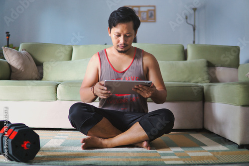 Man in Home Exercise Setting Using Tablet While Practicing Fitness