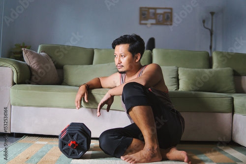 A Man Resting After Exercise Lifting Dumbbells in the Living Room of His House