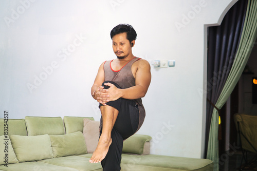 Man Practicing Leg Stretching Exercise Indoors for Fitness and Balance
