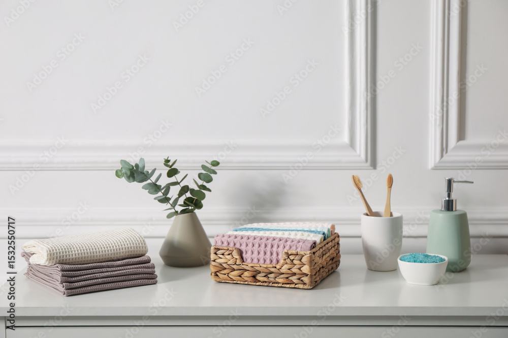 Fototapeta premium Clean waffle towels and other bath products on white dresser in bathroom