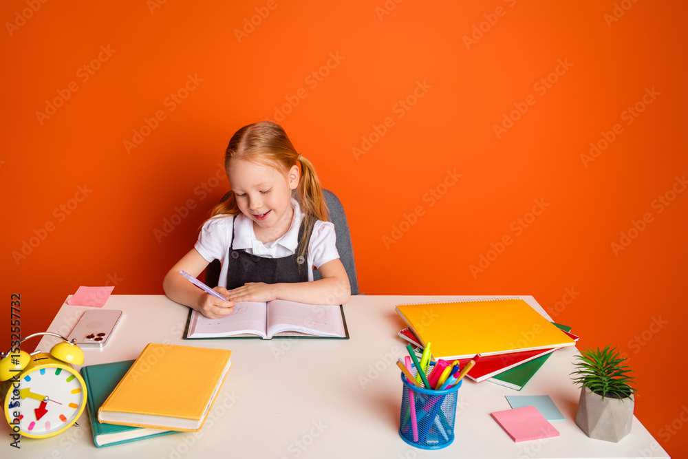 Young schoolgirl writing in her notebook at a white desk surrounded by colorful notebooks and small accessories in a bright setting Young schoolgirl writing in her notebook at a white desk surrounded by colorful notebooks and small accessories in a bright setting