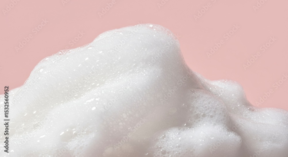 Fototapeta premium Close-up of rich, fluffy white soap foam against a soft pink background