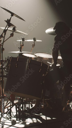 Rehearsal or gig of modern rock band, silhouette of drummer at drum set in darkness, vertical video. Talented musician beating rhythm and expressing emotions, professional drummer striking cymbals