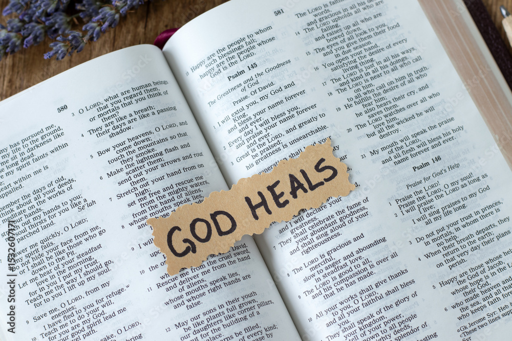 Obraz premium God heals, handwritten quote on top of holy bible book. Top view. Christian biblical concept.