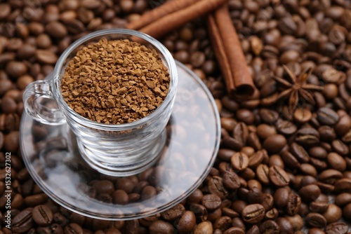 Cup with granulated instant coffee and cinnamon on beans, closeup. Space for text