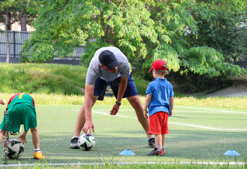  little three-year-old boy plays football at a sports school with a coach.