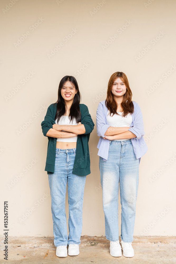 Obraz premium portrait of two teenage girls with arms crossed looking at camera smiling