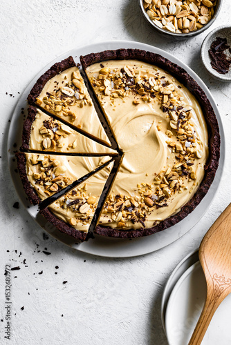 A sliced peanut butter chocolate pie garnished with chopped nuts on a white plate.