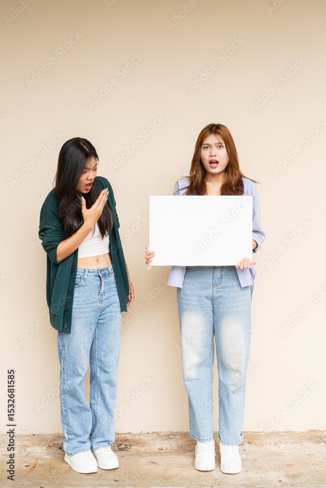 Young women holding blank sign looking shocked Young women holding blank sign looking shocked